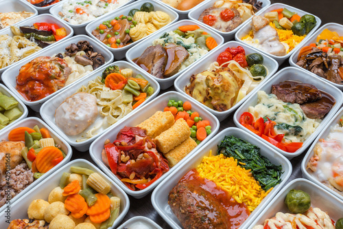 Airplane food presentation with variety of in flight meals. Flight catering. Food on airplanes. Salad bar buffet display in restaurant. Meat cuts. Hot appetizers. Close-up, a lot of food. 