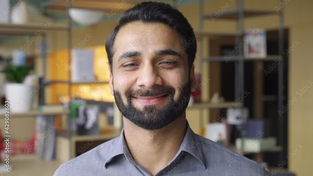 Portrait of young happy indian business man executive looking at camera. Eastern male professional teacher, smiling ethnic bearded entrepreneur or manager posing in office, close up face headshot. Portrait of young happy indian business man executive looking at camera. Eastern male professional teacher, smiling ethnic bearded entrepreneur or manager posing in office, close up face headshot.