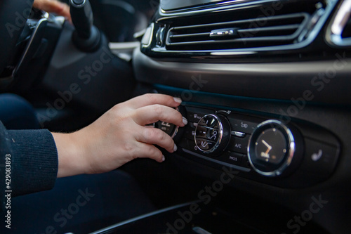 Woman's hand switches the air conditioning in the car. Driver turning on car air conditioning system. moderm climate control system