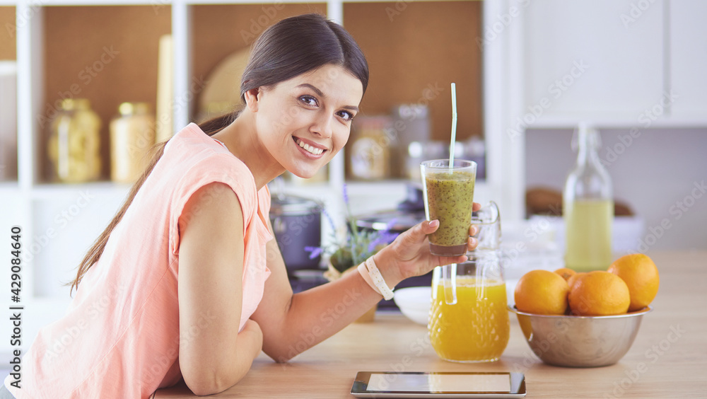 Beautiful young woman using a digital tablet in the kitchen Beautiful young woman using a digital tablet in the kitchen
