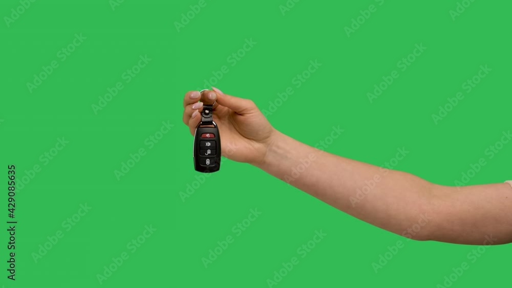 Female hand holding car remote control points his finger at it and