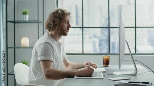 Focused office worker with curly hair draws scheme on tablet photo