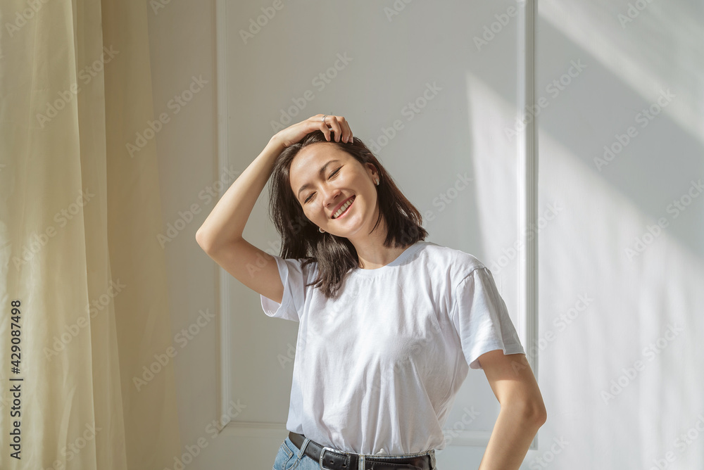 © Асель Иржанова - a young Asian woman with a square hairstyle with black hair and a white T-shirt, jeans. portrait of a happy positive girl © Асель Иржанова - a young Asian woman with a square hairstyle with black hair and a white T-shirt, jeans. portrait of a happy positive girl