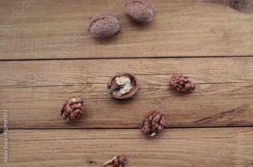 Walnuts lie on a brown wooden surface.