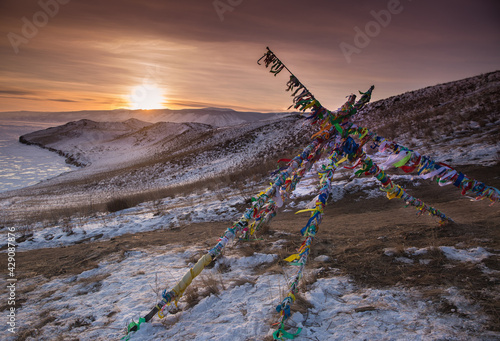 Colored ritual ribbons tied on the tree and wooden poles as a buddhist tradition on Baikal lake
