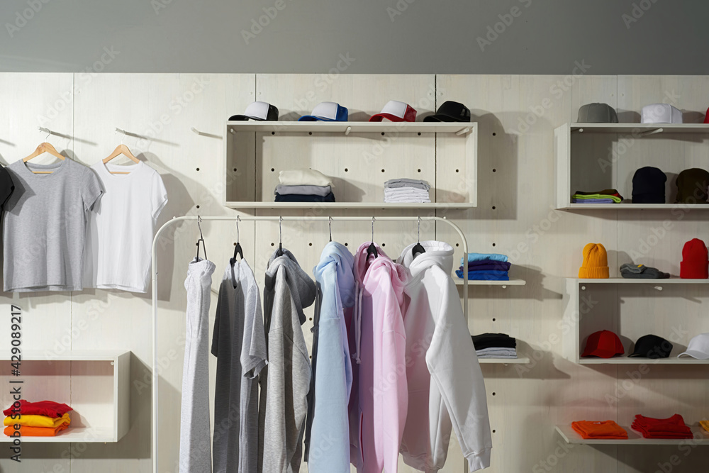 Pastel white, gray, blue and pink cotton sportswear on a rail in the store.  Clothes at custom clothing printing company Stock Photo | Adobe Stock