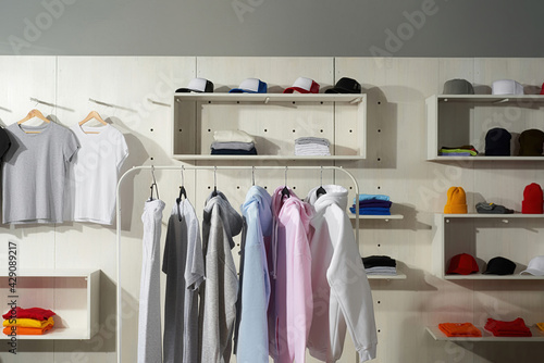 Pastel white, gray, blue and pink cotton sportswear on a rail in the store. Clothes at custom clothing printing company