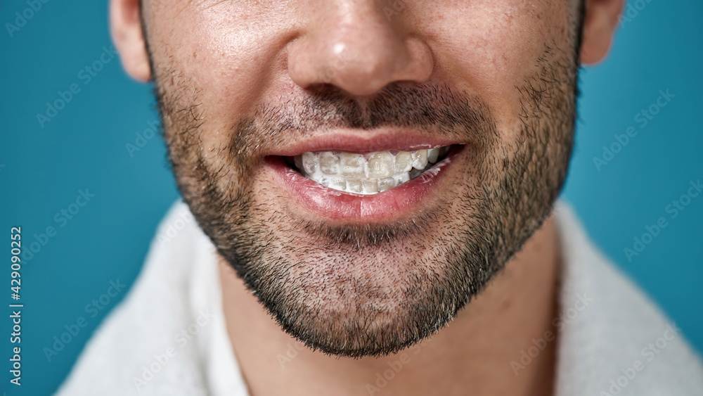 Close up of bearded man smiling at camera with toothpaste in his mouth after brushing teeth isolated over blue background Close up of bearded man smiling at camera with toothpaste in his mouth after brushing teeth isolated over blue background