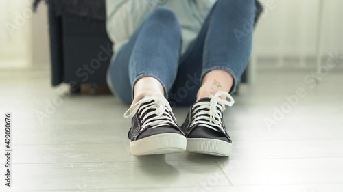 Close-up of a woman's legs in sneakers, a woman sits on the floor and moves her legs Slow motion HD