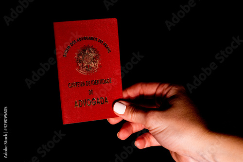 Woman hand holding identification document of lawyer from Brazil. OAB card (Brazilian Bar Association).