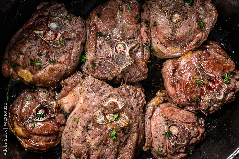 Stewed lamb neck meat in a pan with herbs. wooden background. Top view