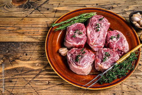 Mutton lamb neck meat on a rustic plate with thyme and rosemary. wooden background. Top view. Copy space