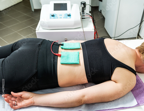 Electro stimulation in physical therapy to a female patient. Medical check at the back in a physiotherapy center. photo