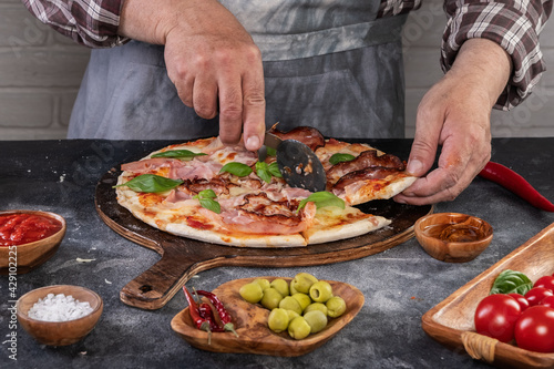 Fototapeta Naklejka Na Ścianę i Meble -  Pizza preparation with chef hands. Pizza making process decorating pizza