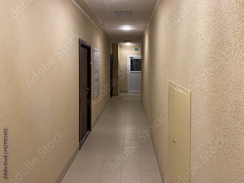 Long narrow yellow beige corridor with apartments in a new modern building