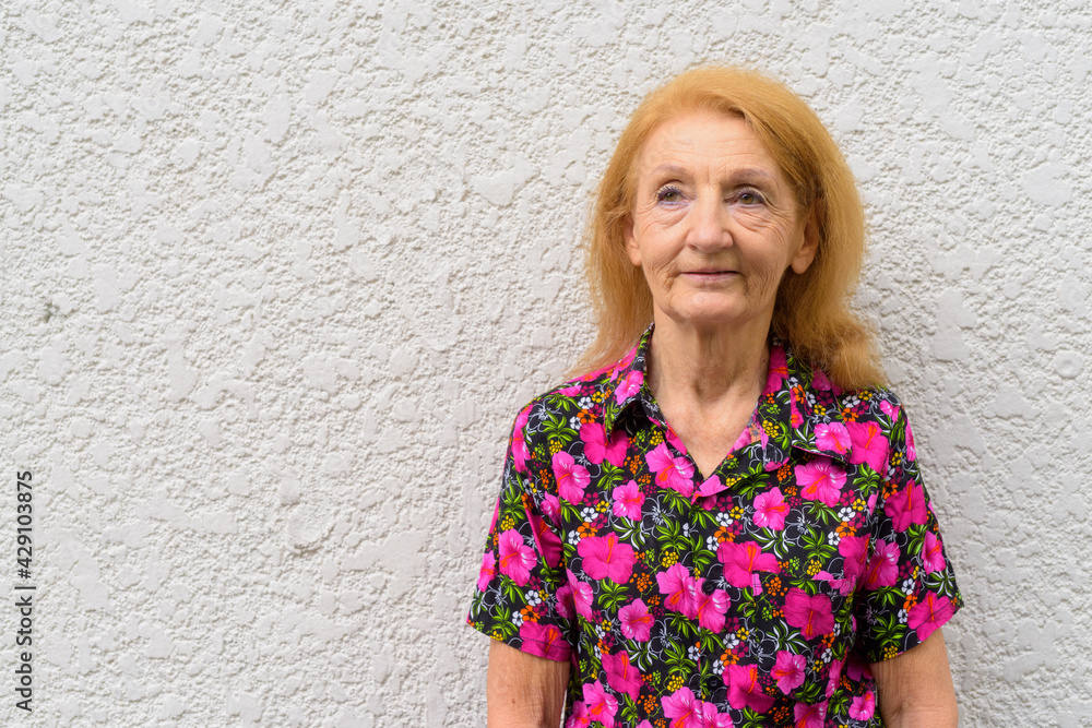 Portrait of a senior woman outdoors during summer thinking against plain wall with copy space Portrait of a senior woman outdoors during summer thinking against plain wall with copy space