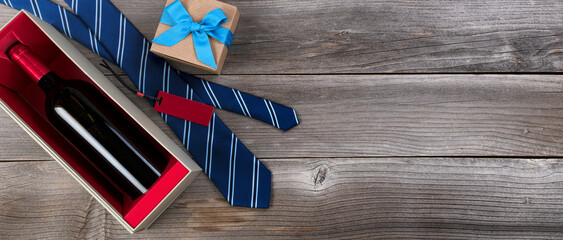 Fathers day concept with blue dress tie, red wine bottle and a giftbox on rustic wooden background