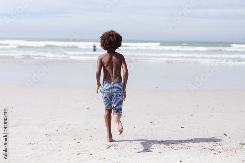 Rear view of african american boy running on the beach