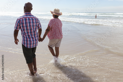 Senior african american couple holding hands walking on the beach