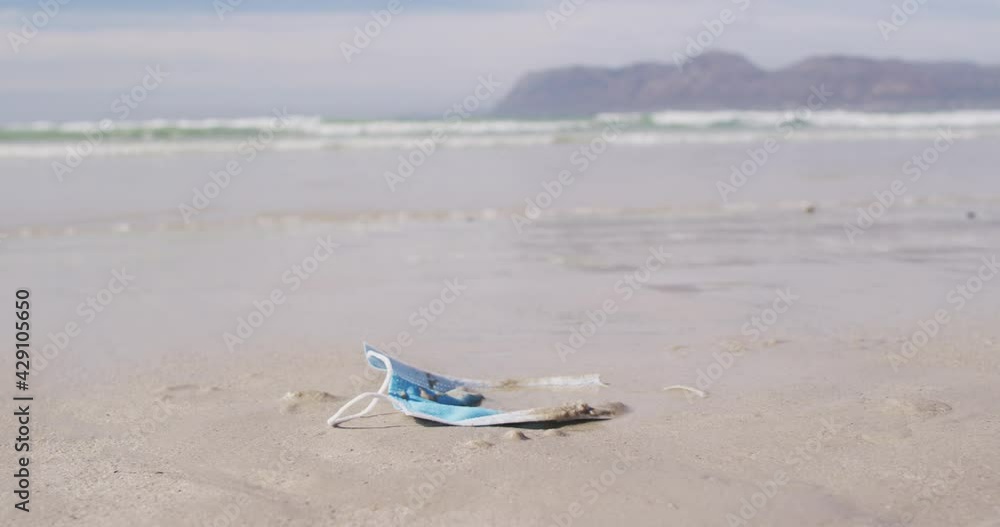 A face mask lying in sand on the beach with waves in the background A face mask lying in sand on the beach with waves in the background