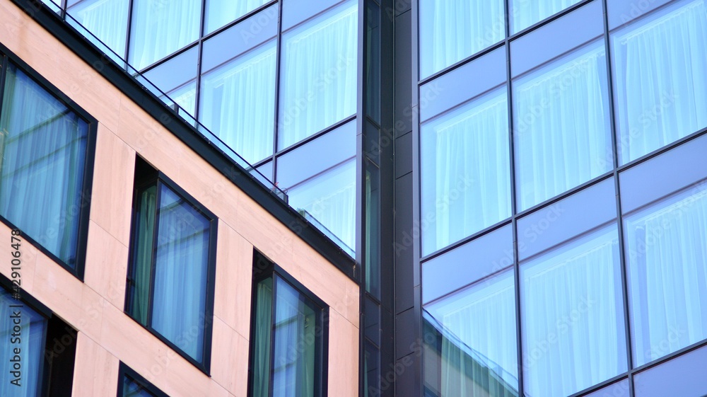 The glazed facade of an office building with reflected sky. Modern architecture buildings exterior background. Clouds sky reflection.