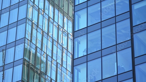 The glazed facade of an office building with reflected sky. Modern architecture buildings exterior background. Clouds sky reflection.