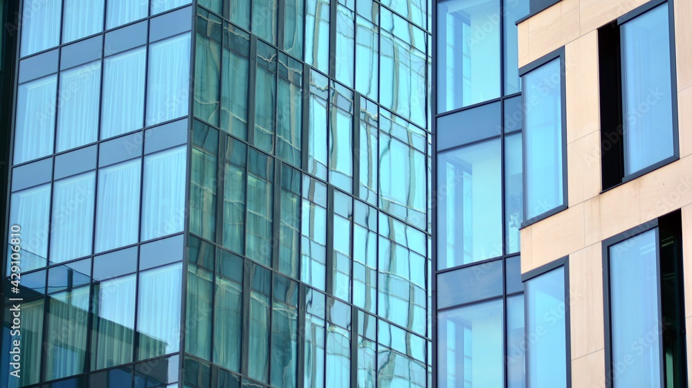 The glazed facade of an office building with reflected sky. Modern architecture buildings exterior background. Clouds sky reflection. The glazed facade of an office building with reflected sky. Modern architecture buildings exterior background. Clouds sky reflection.