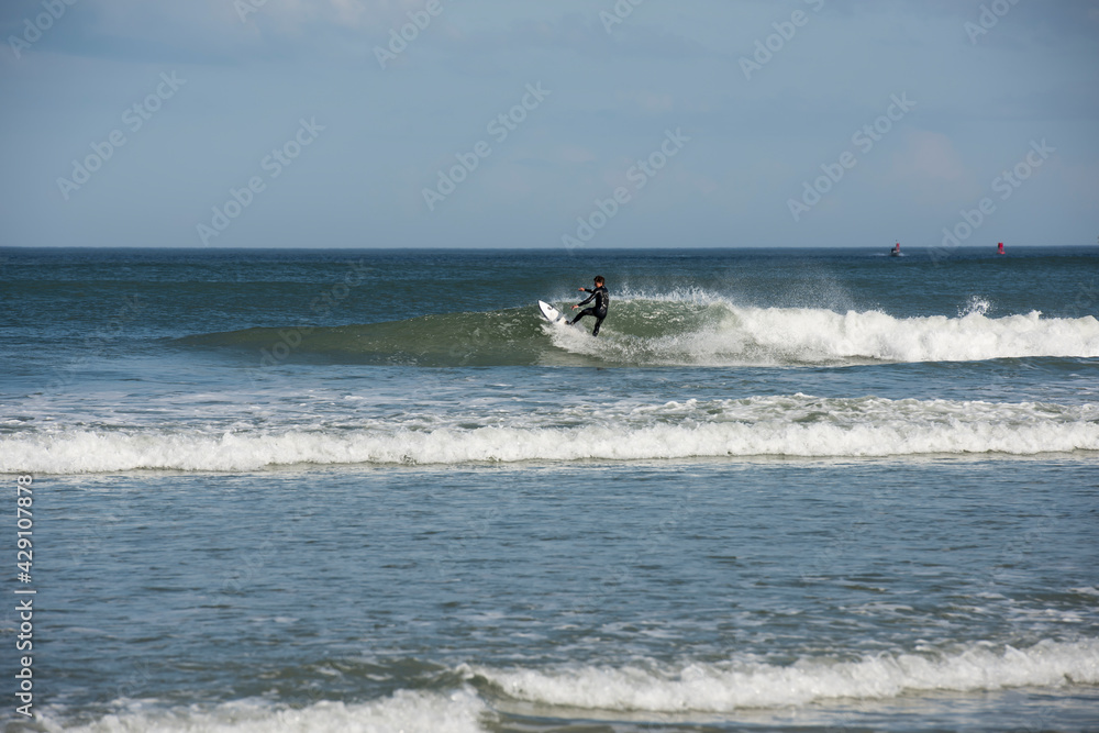 A lone male surfer wearing a black wet suit cutting back on wave as he surfs Florida's east coast near Daytona Beach, USA. A lone male surfer wearing a black wet suit cutting back on wave as he surfs Florida's east coast near Daytona Beach, USA.