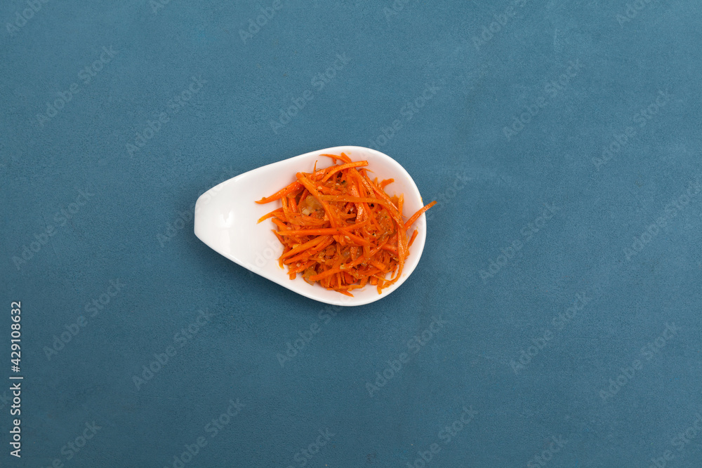 Korean-style vitamin carrot salad, top view. Blue background, copy space Korean-style vitamin carrot salad, top view. Blue background, copy space