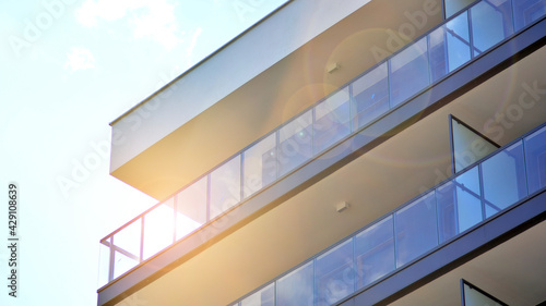 Detail of new luxury house and home complex. Glass surface with sunlight. Rising sun on the horizon. Part of modern residential apartment with flat building exterior. 