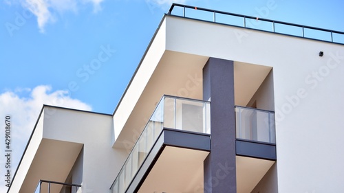 A fragment of modern architecture, walls and glass. Windows and balconies of a residential building against a blue sky. Detail of New luxury house and home complex. Part of city real estate property a