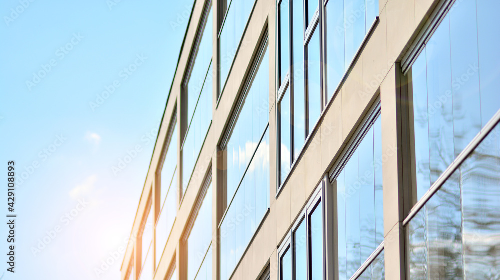 Obraz premium A fragment of modern architecture, walls and glass. Windows and balconies of a residential building against a blue sky. Detail of New luxury house and home complex. Part of city real estate property a