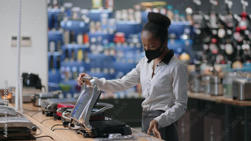 young black woman is reading info on label and tag in home appliances store, choosing electric waffle iron for home cooking young black woman is reading info on label and tag in home appliances store, choosing electric waffle iron for home cooking