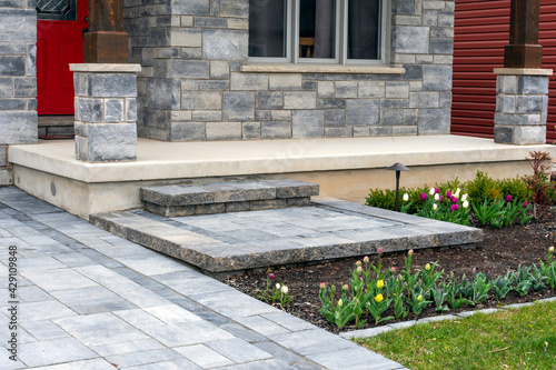 Luxury residential landscaping and front garden shows a precast paver landing, steps and driveway with matching pattern. photo