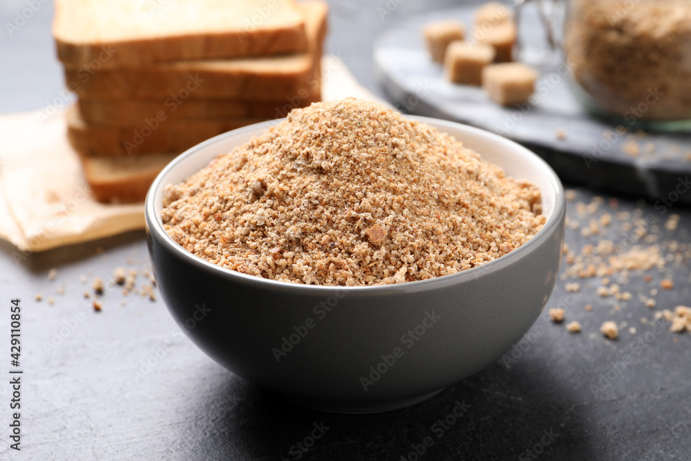 Fresh breadcrumbs in bowl on black table Fresh breadcrumbs in bowl on black table