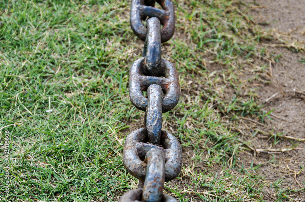 Strong rusted old chain with grass behind Strong rusted old chain with grass behind