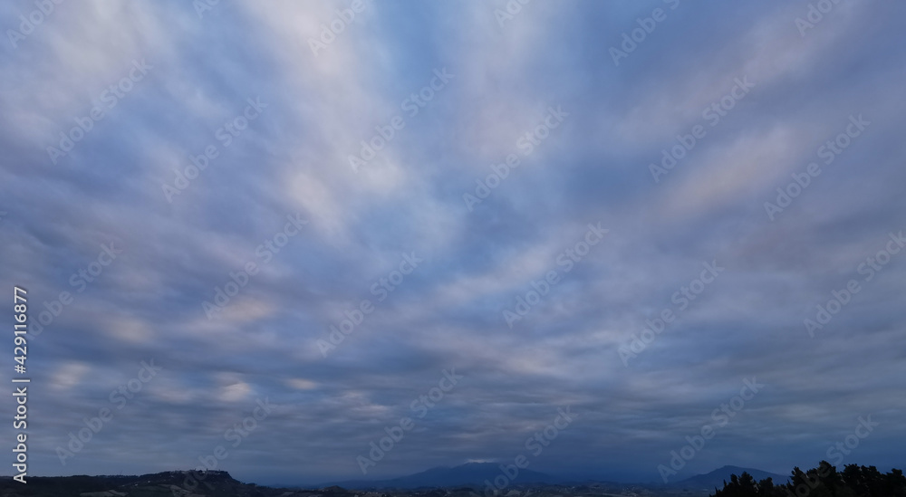 Il cielo ricamato di nuvole sopra le montagne e le colline