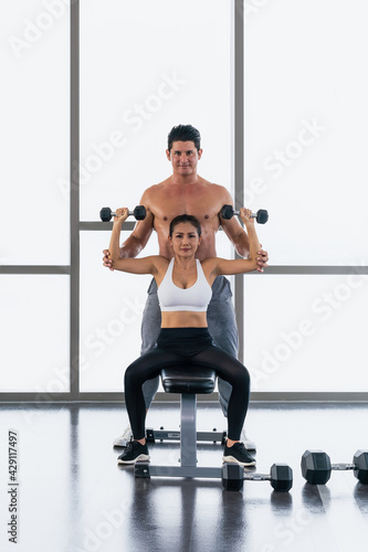 gym trainer coaching athletic woman workout with dumbbell lifting