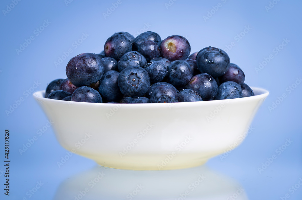 Blueberries in a white bowl on a blue background Blueberries in a white bowl on a blue background