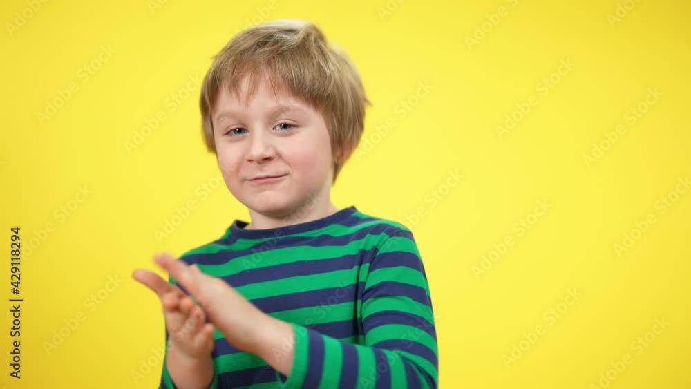 Cute little boy clapping hands looking at camera at yellow background, Portrait of positive Caucasian kid posing and smiling. Happiness and approval concept Cute little boy clapping hands looking at camera at yellow background, Portrait of positive Caucasian kid posing and smiling. Happiness and approval concept