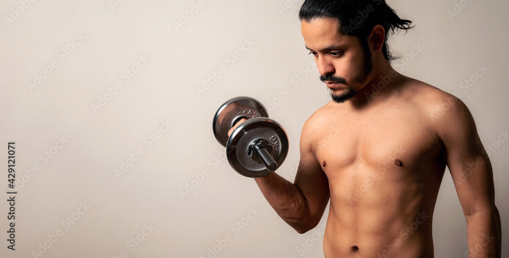 Young latin fitness man holding a metal dumbbell on a clear background with copy space