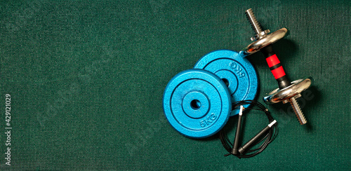 High angle view of exercise weights on a dark green blanket with copy space. Low light. Fitness equipment for exercising at home