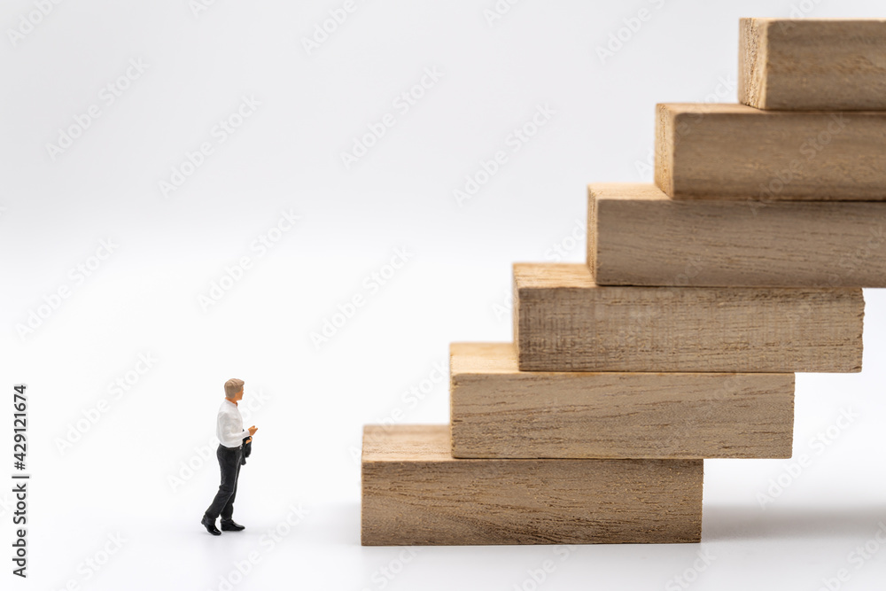 Business and Planning Concept. Businessman miniature figure people walking to stack of wooden block toy on white background. Business and Planning Concept. Businessman miniature figure people walking to stack of wooden block toy on white background.