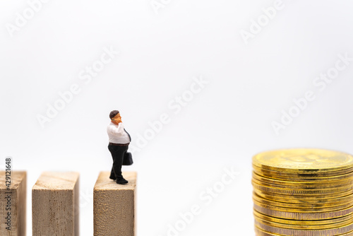Business, Money Investment and Planning Concept. Fat businessman miniature figure people make a phone call and walking on wooden block to stack of gold bitcoin coins on white background.
