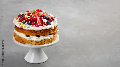 Delicious homemade cake with fresh berries and mascarpone cream on gray background.