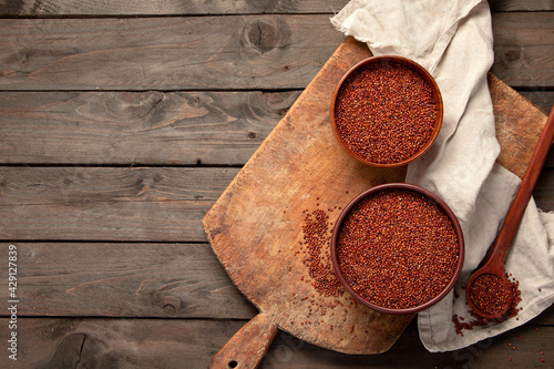 Red quinoa seeds on wooden background. Healthy vegan food concept.