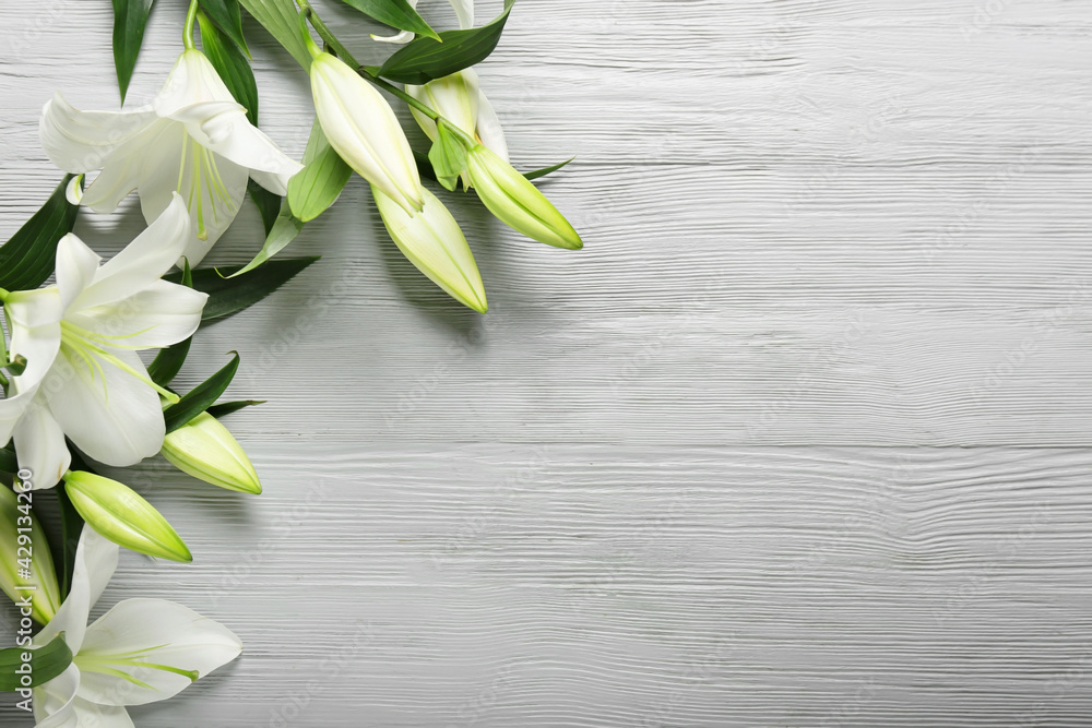Beautiful lily flowers on light wooden background Beautiful lily flowers on light wooden background