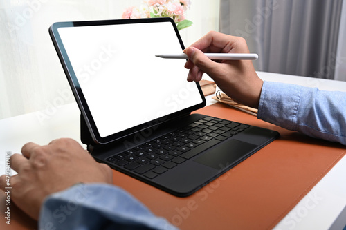 Close up view man holding stylus pen writing on empty screen of computer tablet.