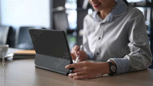 Cropped shot of businesswoman searching information on computer tablet at office desk.
