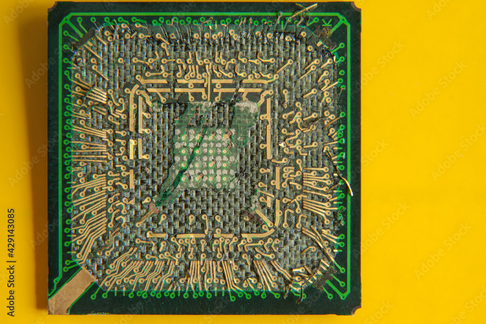 Fototapeta premium An old broken computer CPU with a torn chip on a yellow background